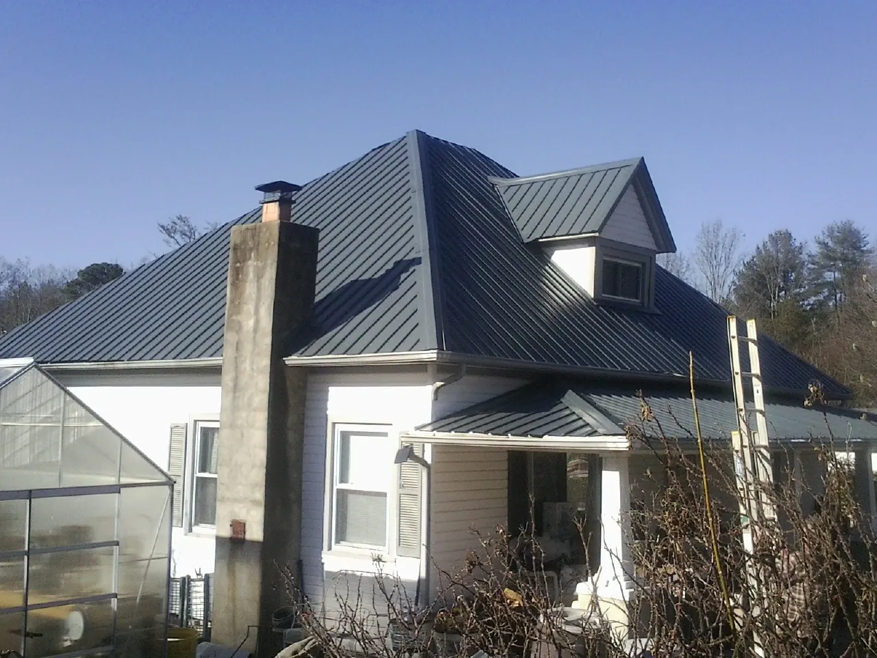 Dark blue standing seam metal roof on a white farmhouse with dormer — Slate & Tile Roof Repair by Roofing Brothers in Duncan Falls