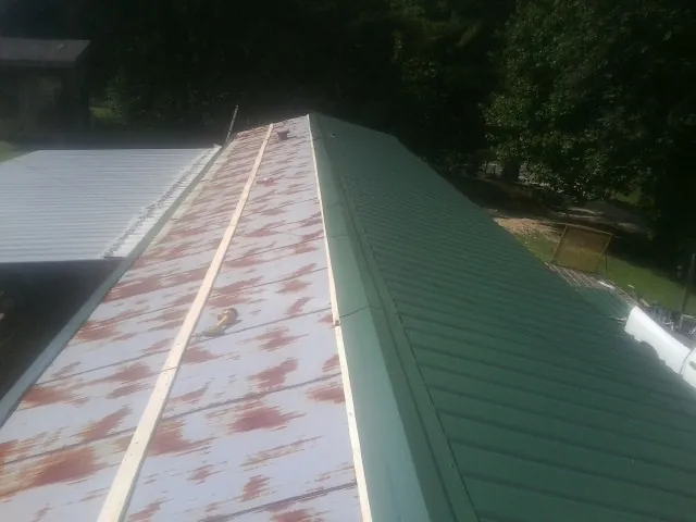 Old rusted panels beside newly installed green metal roofing — Wind Damage Roof Repair by Roofing Brothers in Duncan Falls
