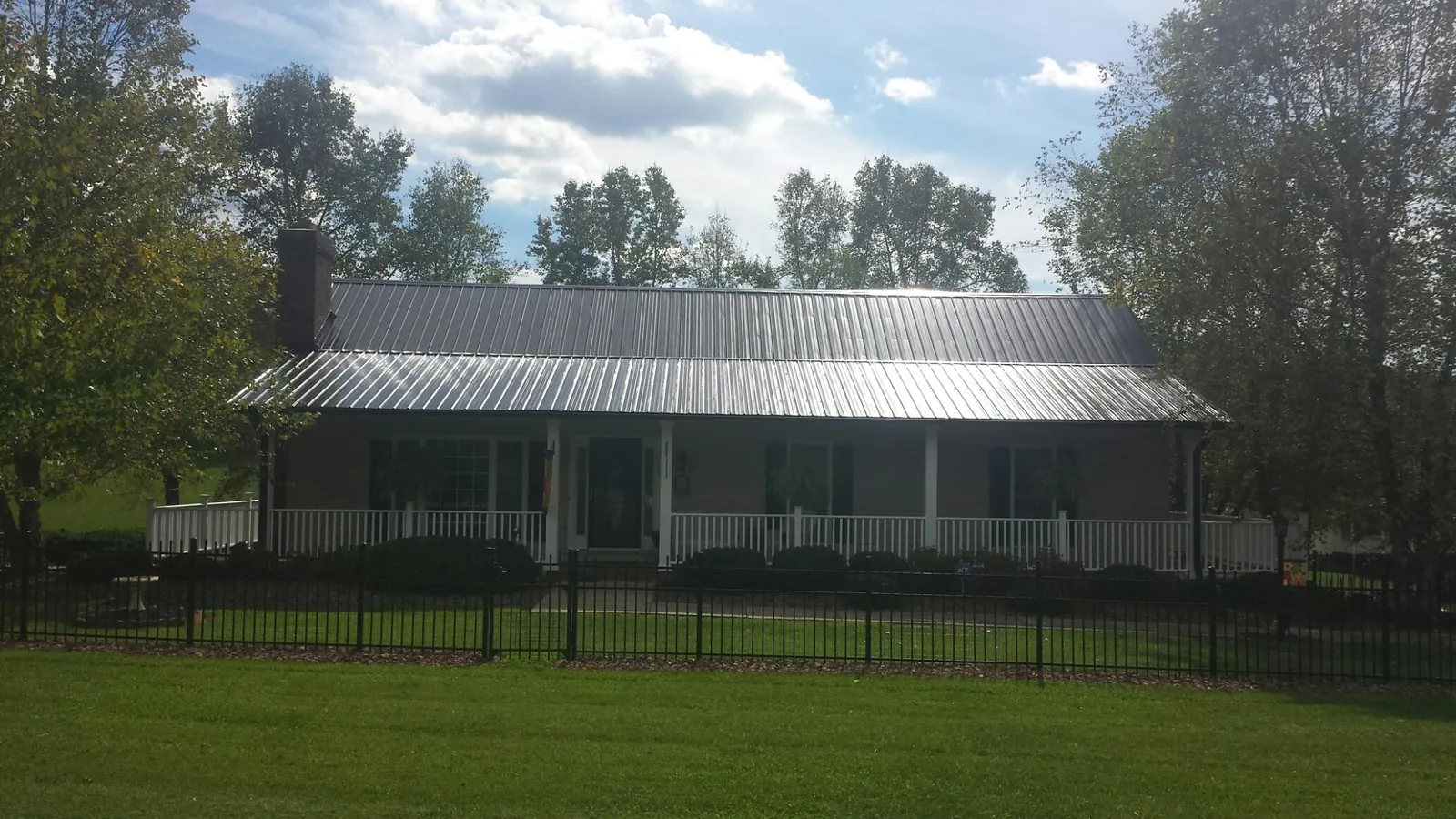 Gray metal roof on a brick ranch with a full width front porch — Gutter Guard Installation work by our crew in Duncan Falls