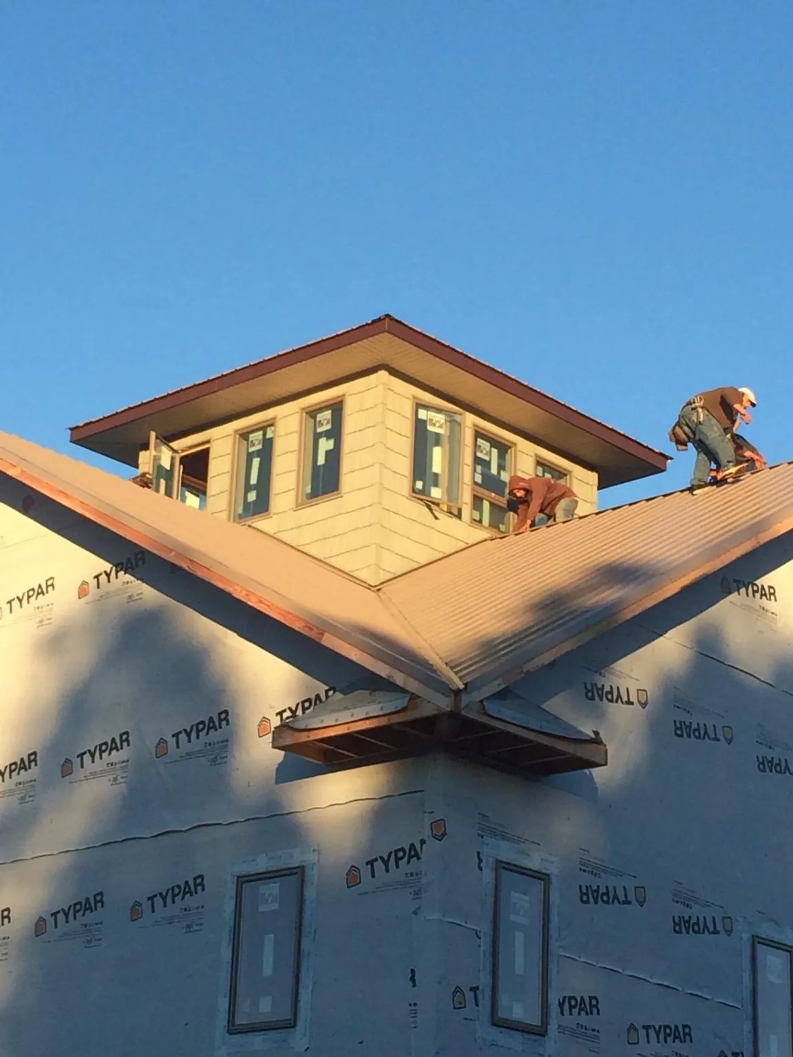 Roofers working around a rooftop cupola on a new metal roof at sunset — Roof Waterproofing in Duncan Falls by Roofing Brothers